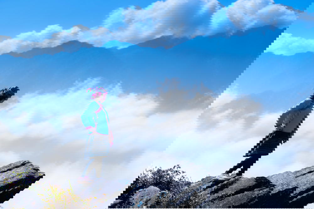 A woman standing on top of a mountain in Sapa, Vietnam, overlooking the clouds.