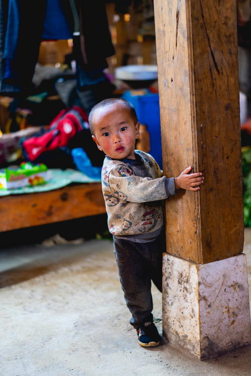 A young boy leaning against a wooden pole in Vietnam.