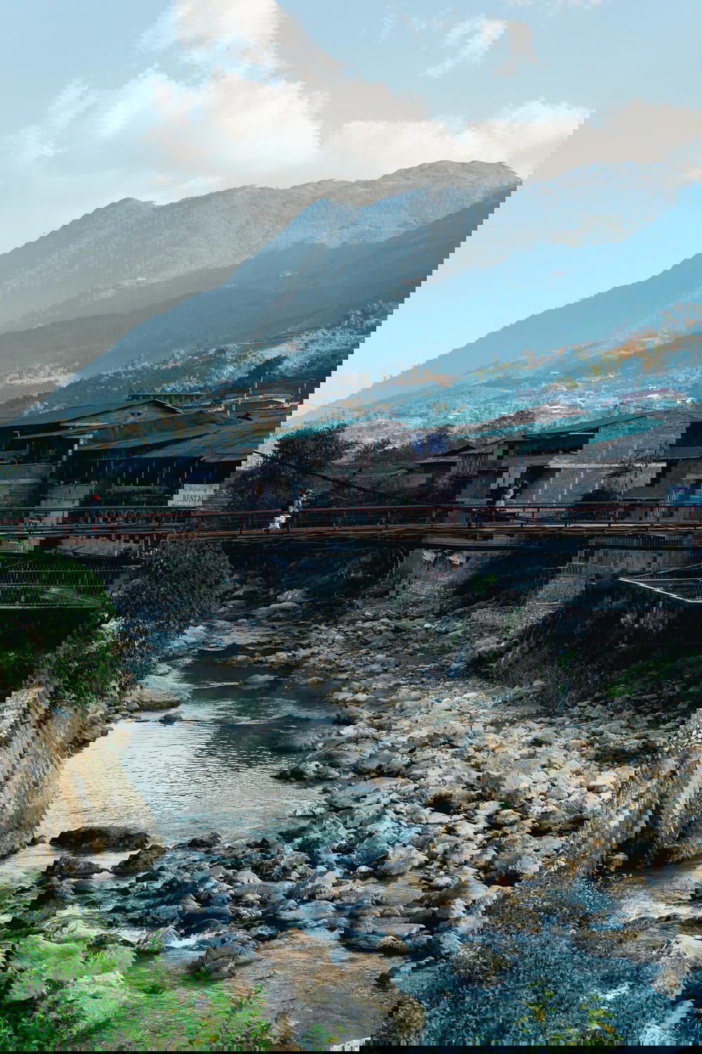 People walking across a shallow river in a town near Sapa, Vietnam