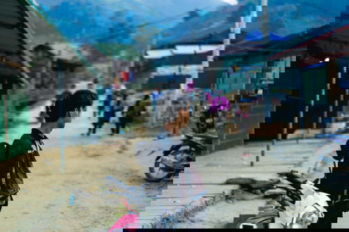 A man standing next to a motorcycle on a dirt road in Vietnam.